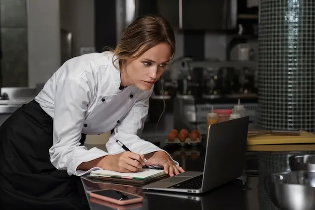 Female chef in the kitchen using a laptop